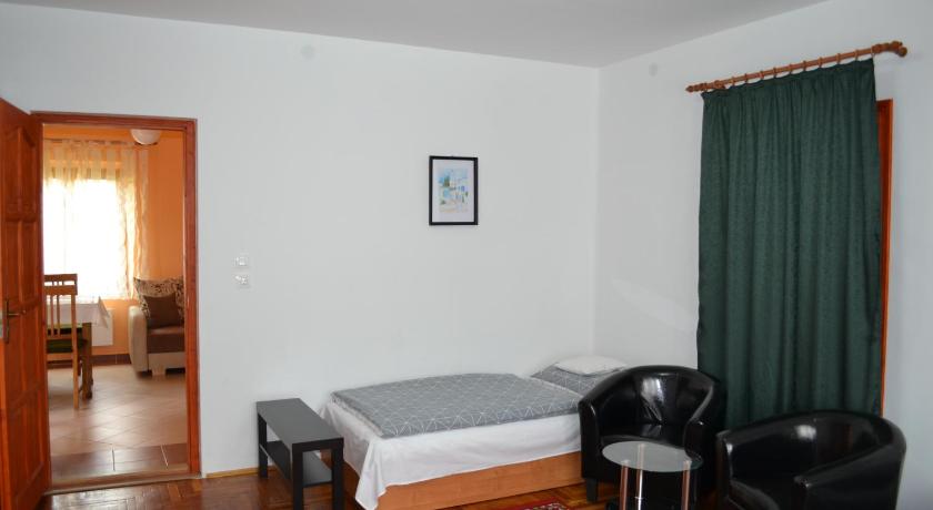 a room with a bed, chair, table and a lamp, Liliom Apartman in Gyula