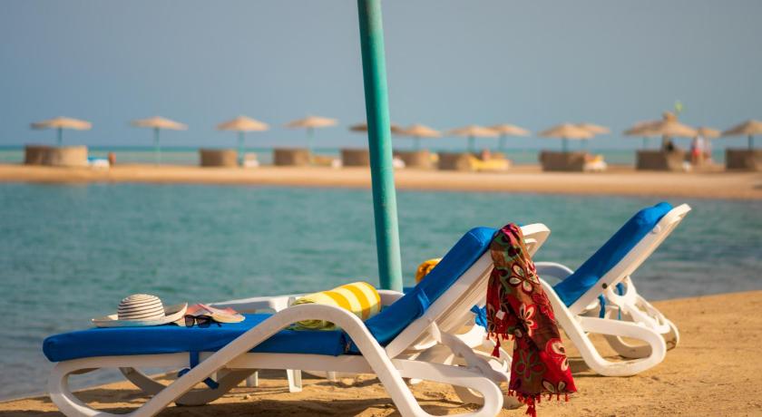 a woman sitting on a beach chair next to a beach, Movenpick Resort & Spa El Gouna in Hurghada