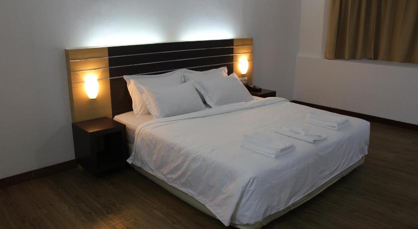 a white bed with a white headboard and pillows, SARA HOTEL in Labuan