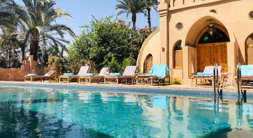 a beach with a pool, chairs, and a pool table, Embrace Hotel in Luxor