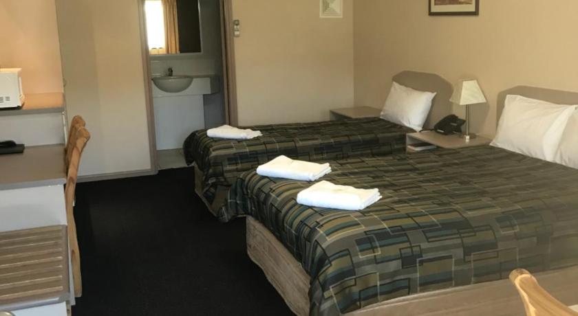 a hotel room with a bed, desk and a lamp, The Bakehouse Motel in Goulburn