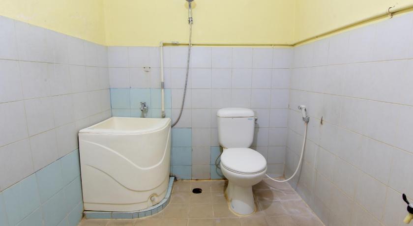 a white toilet sitting next to a white bath tub, Hotel Puspita in Yogyakarta