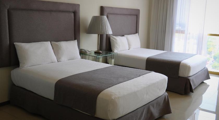 a hotel room with two beds and two lamps, Hotel Suites Bernini in Guadalajara