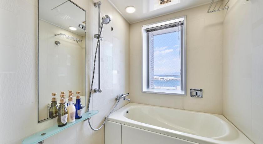 a bathroom with a tub, sink, mirror and bathtub, HOTEL MYSTAYS Shimizu in Shizuoka