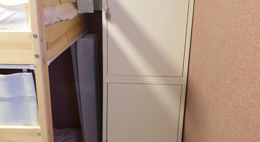 a small room with a refrigerator and a bed, Sagye Travel Guesthouse in Jeju