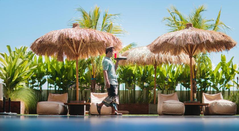 a man standing on top of a beach holding an umbrella, Mahogany Hotel in Bali