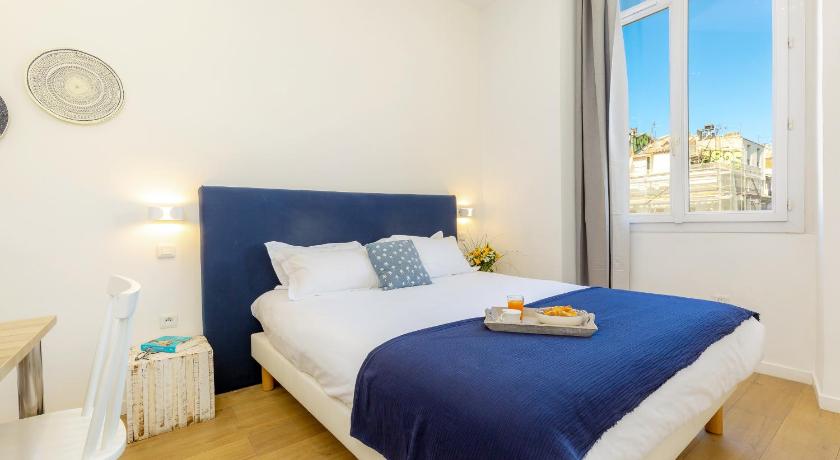a white bed sitting in a bedroom next to a window, Breteuil – Appart au Vieux Port in Marseille