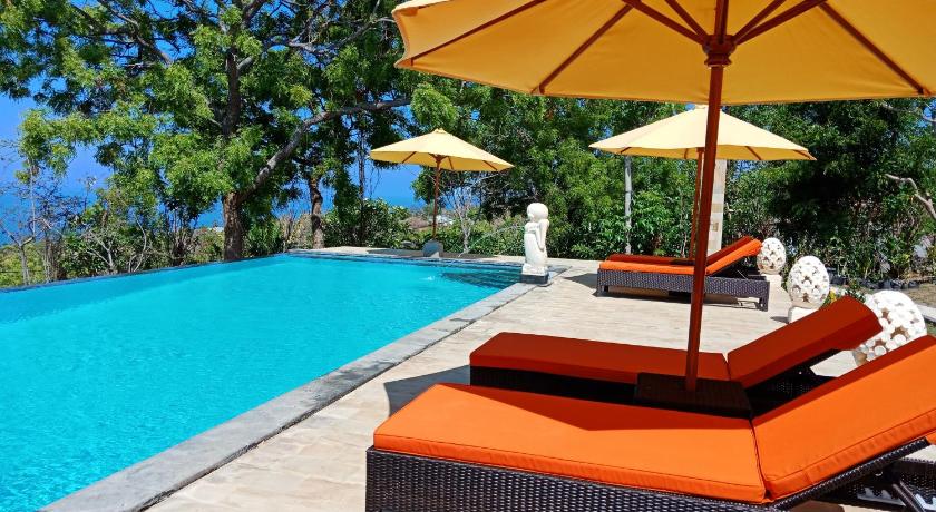 a lounge chair sitting on top of a beach next to a pool, Samari Hill Villa in Bali