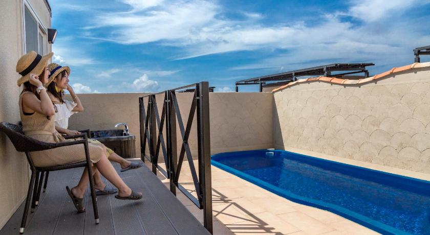 a woman sitting on a balcony looking at her cell phone, Ocean's Resort Villa Vorla in Miyakojima