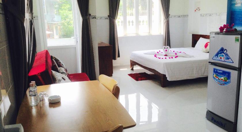 a room with a bed, chair, table and a television, Queen Motel Vung Tau in Vung Tau