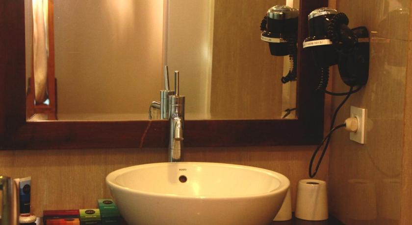 a white sink sitting under a mirror in a bathroom, Hotel Dafam Linggau in Lubuklinggau