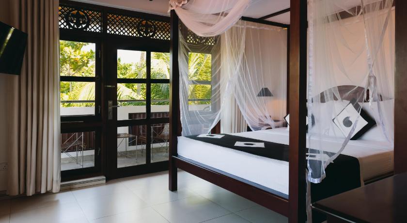 a bedroom with a bed and a canopy, Amal Beach Hotel in Bentota