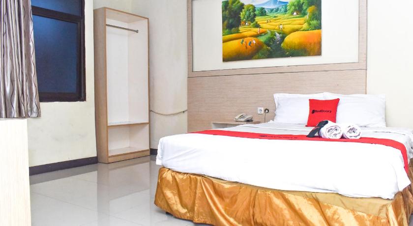 a hotel room with a bed, desk and a painting on the wall, RedDoorz Plus near Sultan Hasanuddin Airport in Makassar