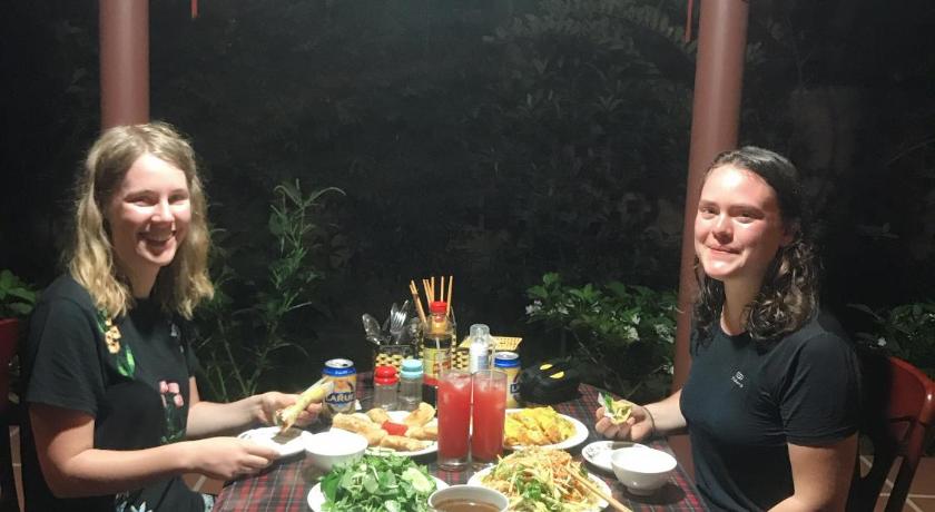 two women sitting at a table with plates of food, Countryside Garden Homestay in Hoi An