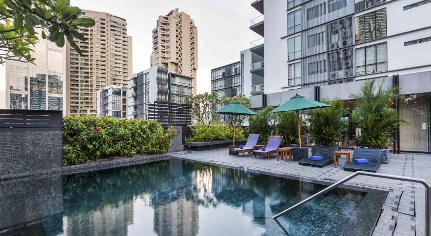 a patio area with a pool, lawn chairs, and a large building, Maitria Hotel Sukhumvit 18 Bangkok – A Chatrium Collection in Bangkok