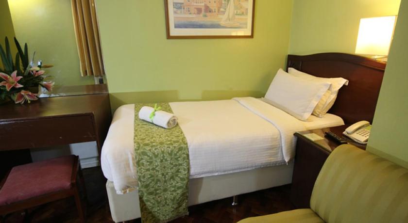 a hotel room with a bed and a chair, The Corporate Inn Hotel in Manila