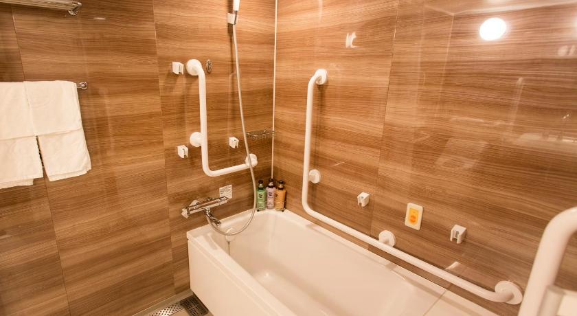 a bathroom with a bathtub, sink and mirror, Hotel Monterey Le Frere Osaka in Osaka