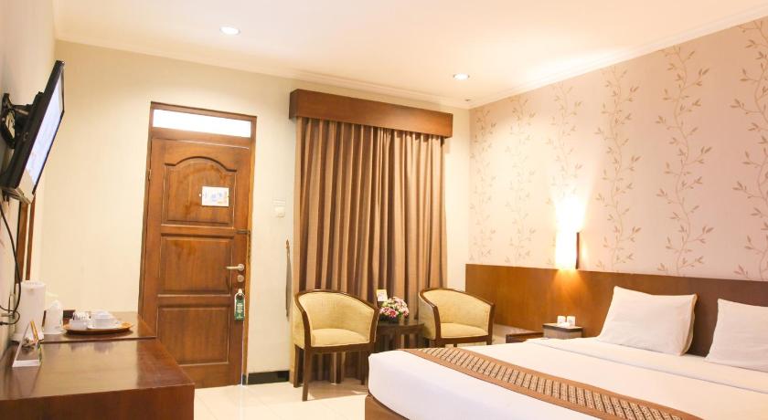 a hotel room with two beds and a television, Cakra Kembang Hotel Yogyakarta in Yogyakarta