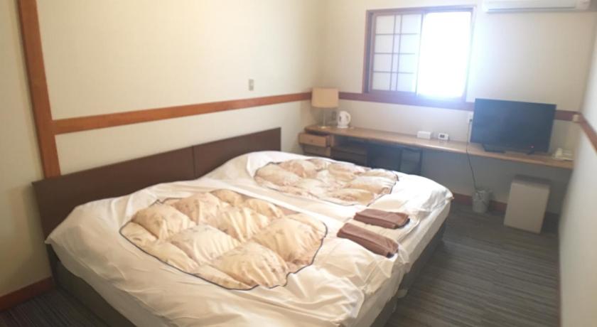 a bed in a room with a white bedspread, Hotel Nasu Otawara Hills in Nasushiobara