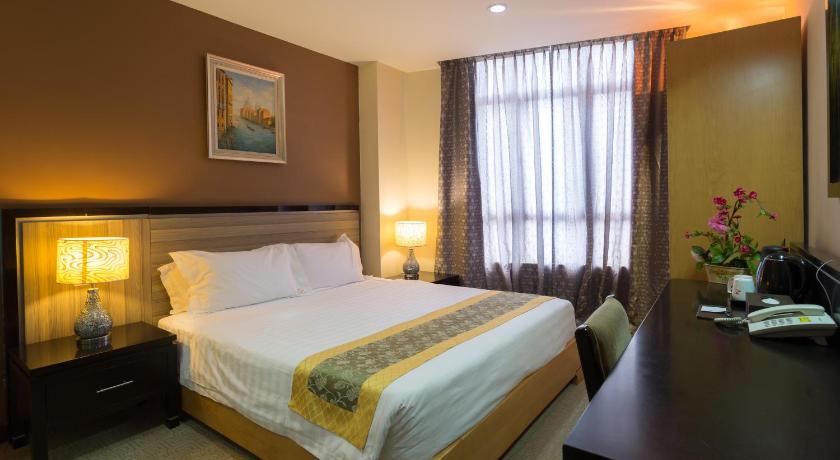 a hotel room with a large bed and two lamps, Hallmark View Hotel in Malacca