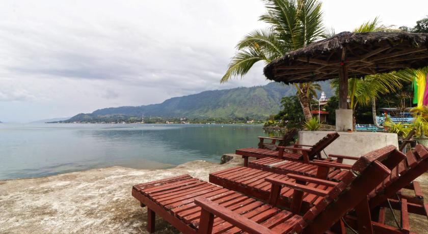 a row of wooden benches sitting on top of a beach, Bagus Bay Guest House in Samosir