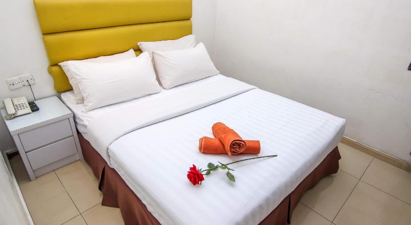 a bed with a white bedspread and pillows on top of it, Rose Cottage Hotel Impian Senai in Johor Bahru