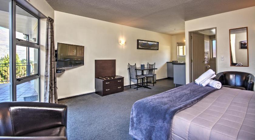 a hotel room with a bed and a television, Alexis Motels and Apartments in Queenstown