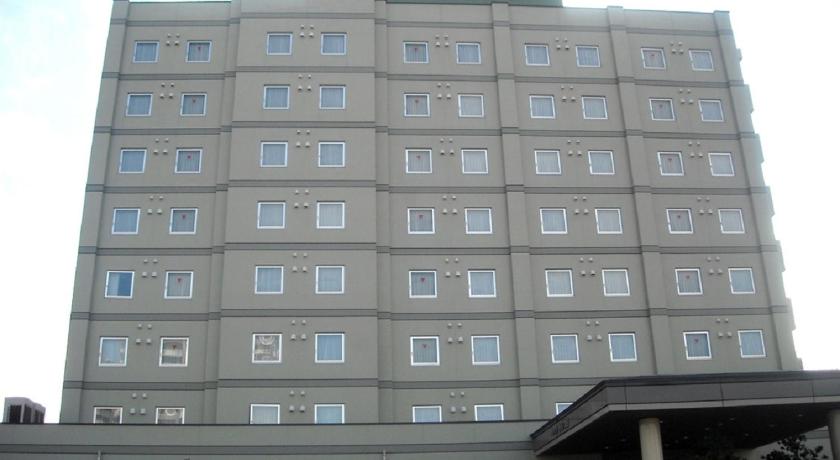 a large building with a clock on the front of it, Hotel Route Inn Honjo Ekiminami in Honjo