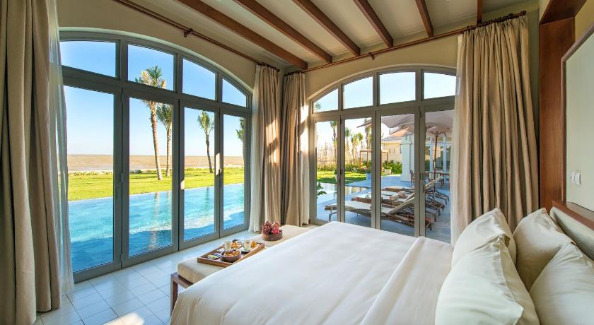 a bedroom with a large bed and a large window, FLC Luxury Resort Samson in Thanh Hoá / Sầm Sơn Beach