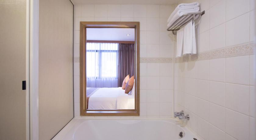 a white bath tub sitting in a bathroom next to a window, The Tarntawan Hotel Surawong Bangkok in Bangkok