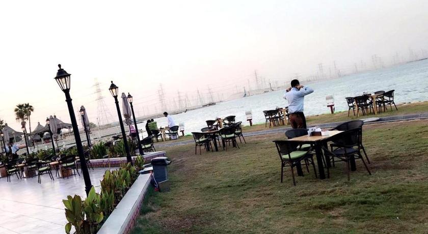 a person sitting at a picnic table in front of a body of water, Lafontaine Le Lac Resort in Dhahran