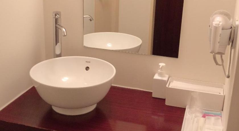 a bathroom with a sink, toilet and mirror, Hills Hotel Gotanda in Tokyo