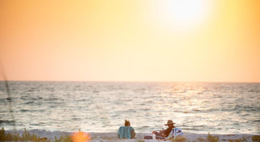 two people sitting on a beach next to the ocean, Belleair Beach Club in Belleair Beach (FL)