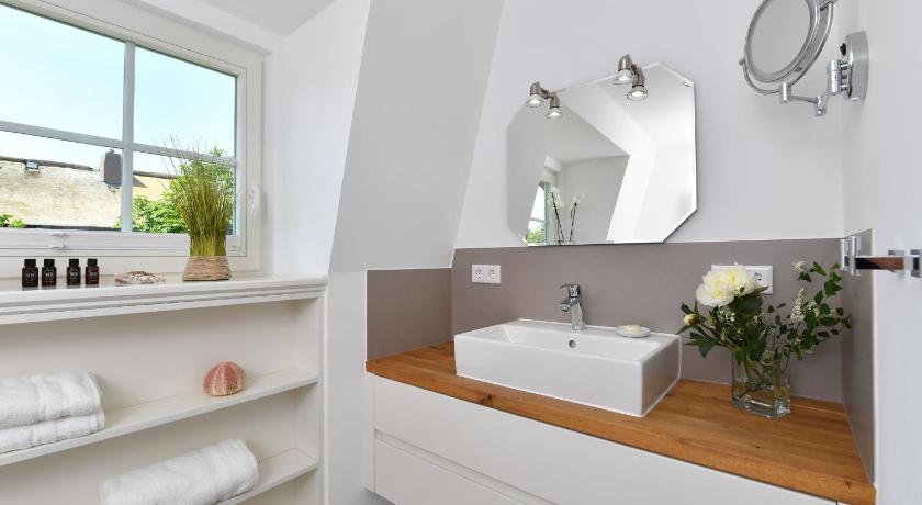 a bathroom with a sink, mirror and bath tub, Ferien Domizil Suderstraße 20 in Sylt Ost