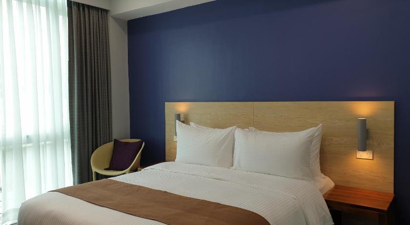 a bedroom with a white bed and a blue wall, Leez Inn Makati in Manila