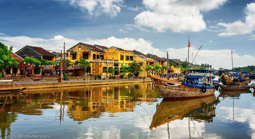 boats are docked in the water near a small town, Redrose Villa in Hoi An