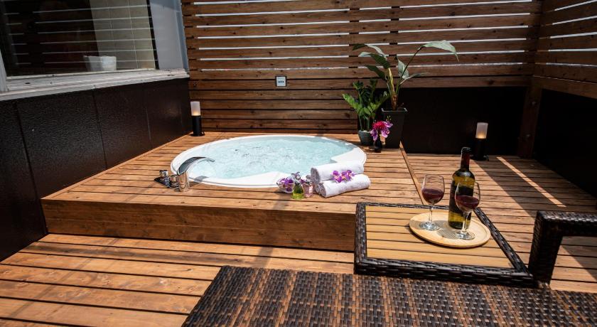 a wooden table with a bath tub and a vase of flowers, Hotel Aqua Kiss Moriyama (Adult Only) in Kusatsu-shi
