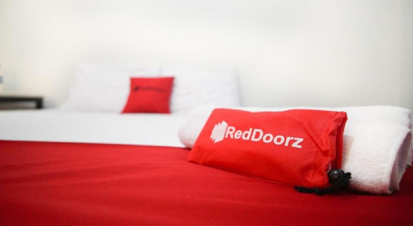 a bed with a red blanket and pillows on it, RedDoorz near Mal Abepura in Irian Jaya / Papua