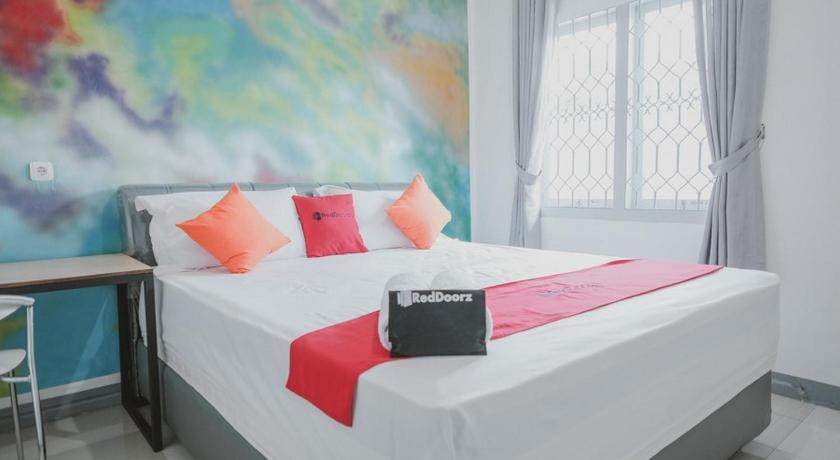 a bedroom with a large bed and a painting on the wall, RedDoorz @ Beringin Jambi in Jambi