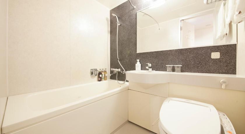 a white toilet sitting next to a bath tub in a bathroom, Richmond Hotel Sapporo Odori in Sapporo