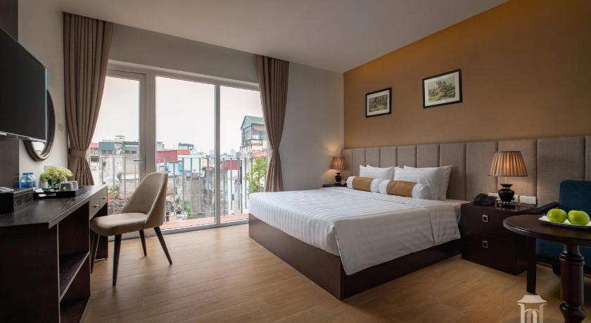 a bedroom with a large bed and a large window, The Hanoian Hotel in Hanoi
