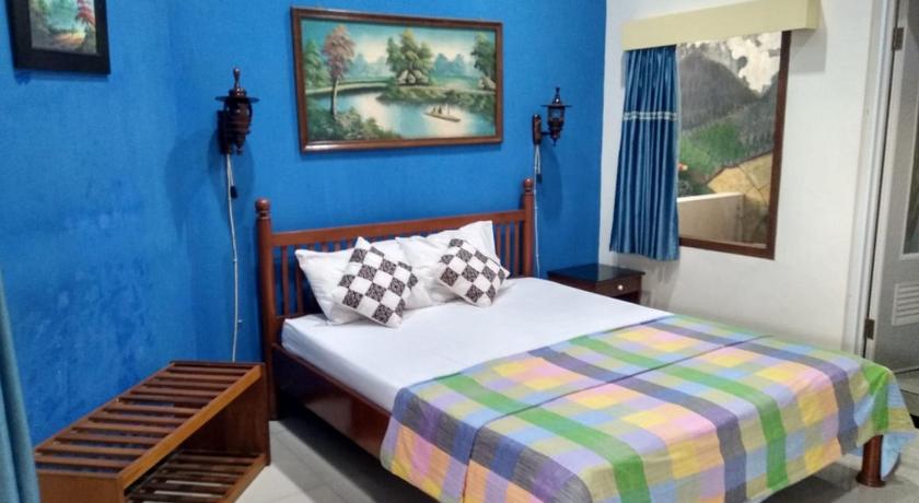 a bedroom with a bed and a painting on the wall, Enny's Guest House in Malang