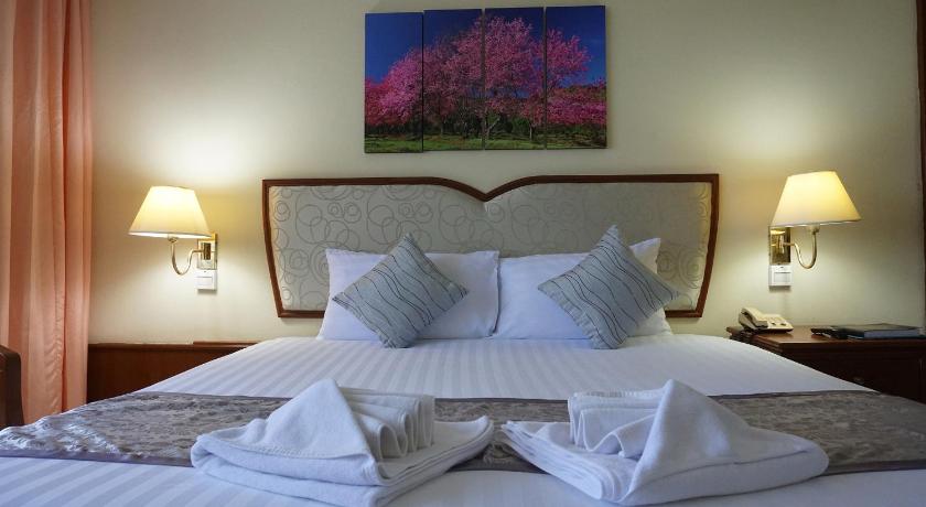 a hotel room with a large bed and two lamps, Wattana Park Hotel in Trang