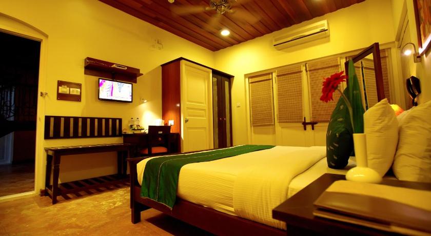 a hotel room with a bed and a television, Tea Bungalow in Kochi