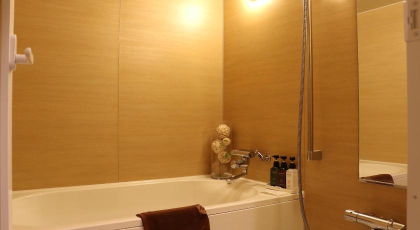 a bathroom with a tub, toilet, sink and mirror, Nipponbashi LUXE HOTEL in Osaka