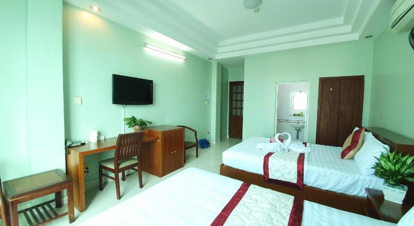 a hotel room with two beds and a table, Truong Son Hotel in Ho Chi Minh City