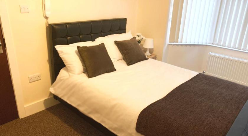 a bed with a white comforter and pillows, Serviced Accommodations in Luton
