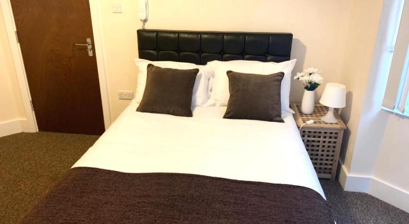 a bed with a white blanket and pillows on top of it, Serviced Accommodations in Luton