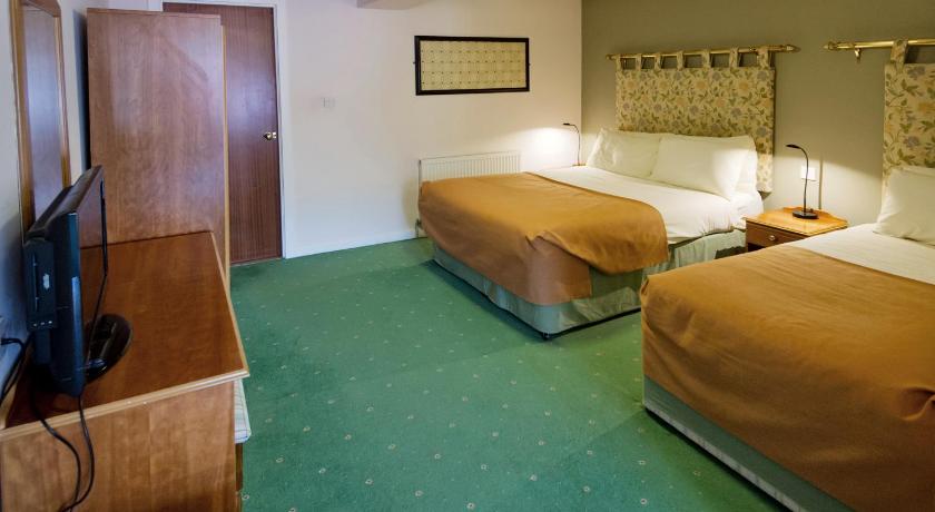 a hotel room with two beds and a television, Station Hotel in Thurso