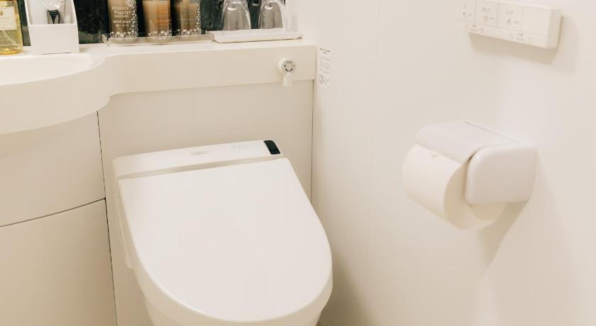 a white toilet sitting next to a white sink, The Celecton Kurashiki Mizushima in Kurashiki